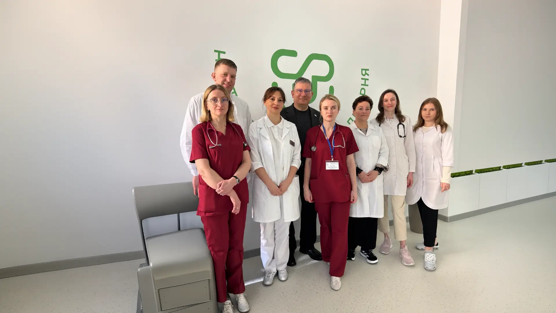 Ukrainian medical team in white coats and red scrubs standing together in a hospital room with CMA-supported care visible